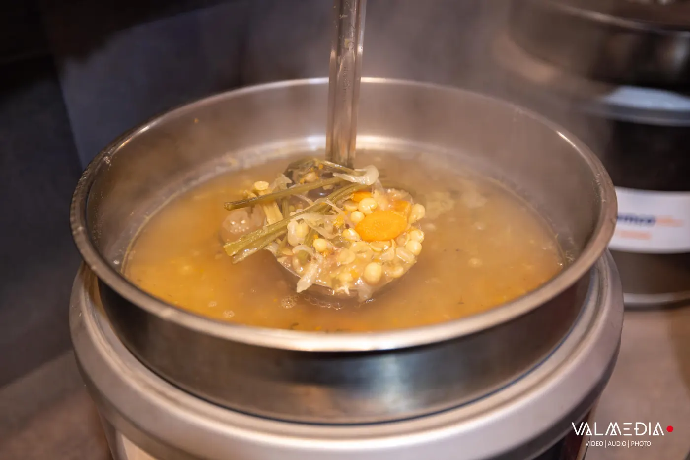 Une louche de soupe aux pois, aux légumes et aux carottes, dans la marmite fumante.