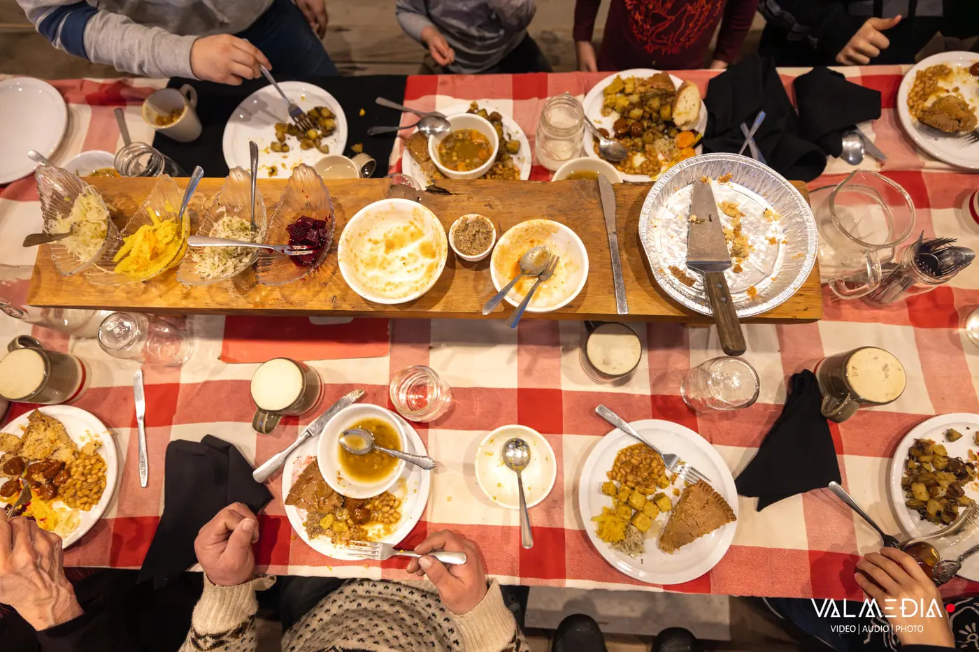 La tablée vue d'en haut, pleine : tourtière, fèves, patates et soupe sur une nappe à carreaux rouge et blanc.