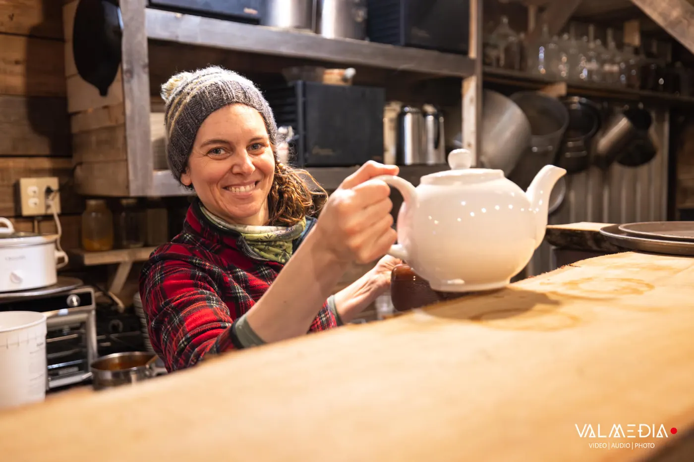 Audréanne sourit en tenant une théière blanche, au comptoir de la cuisine.